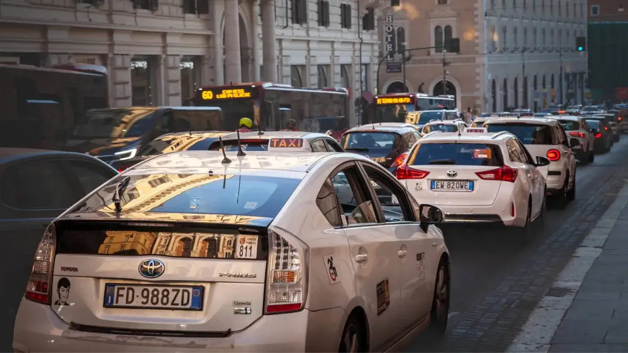 Verkehr in Rom: Mehrere italienische Taxis stehen im Stau. Ein wei&szlig;er Toyota Prius mit der Aufschrift 