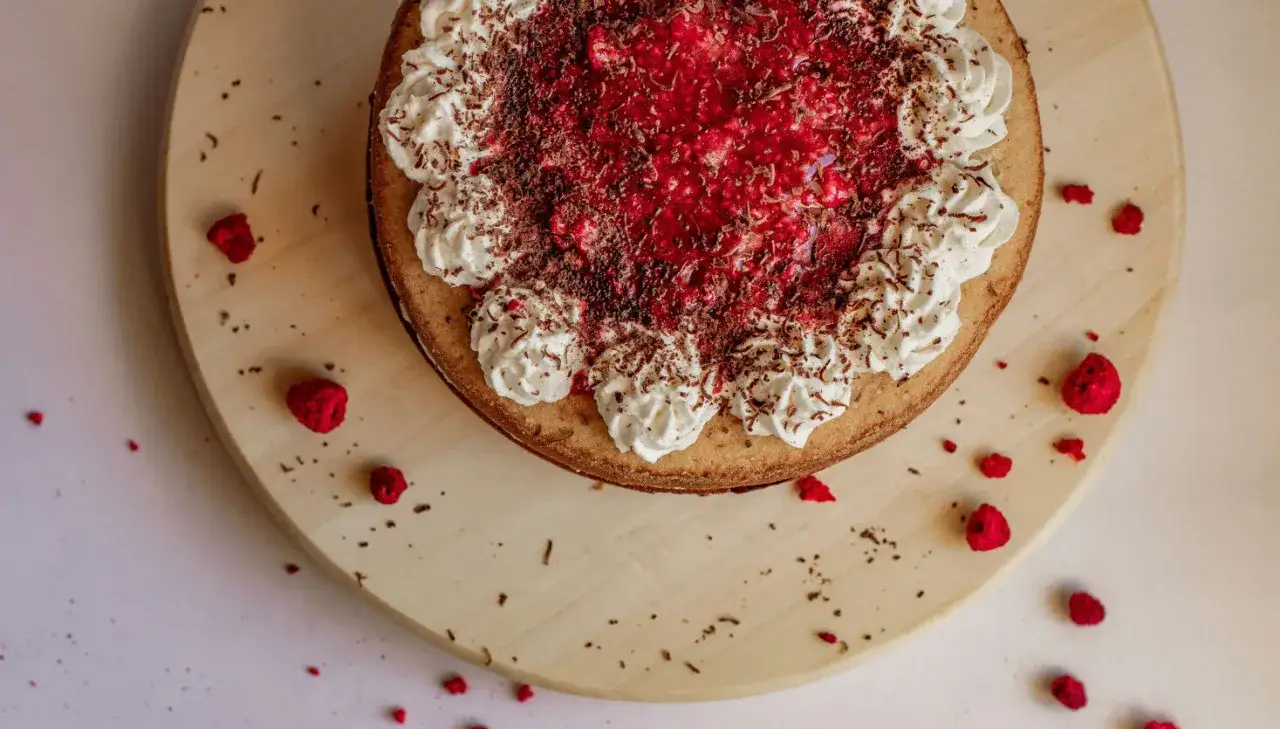 Eine k&ouml;stliche Kokos Torte mit Himbeeren und Sahne, bestreut mit Schokostreuseln.