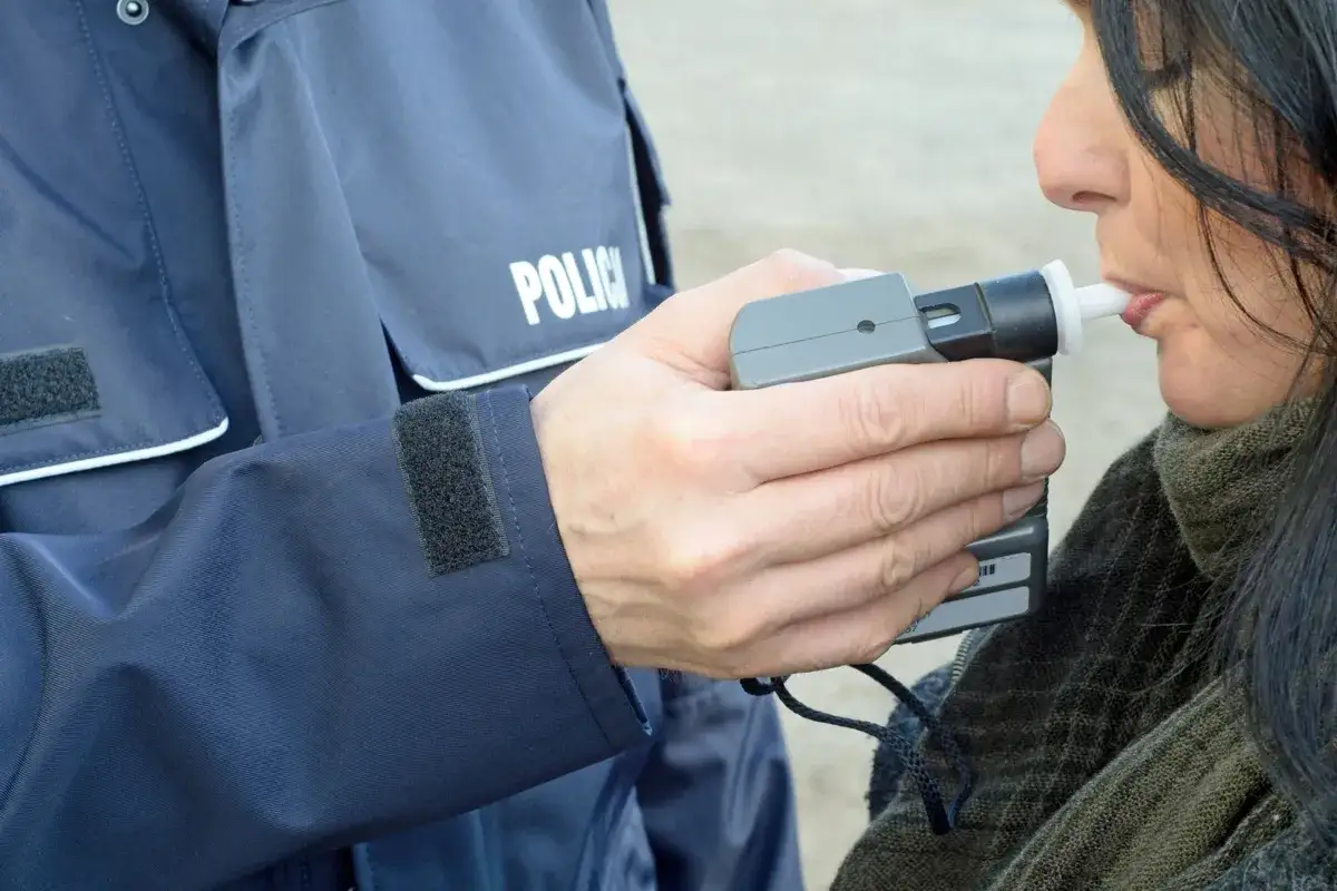 osoba dmuchająca w alkomat z ustnikiem