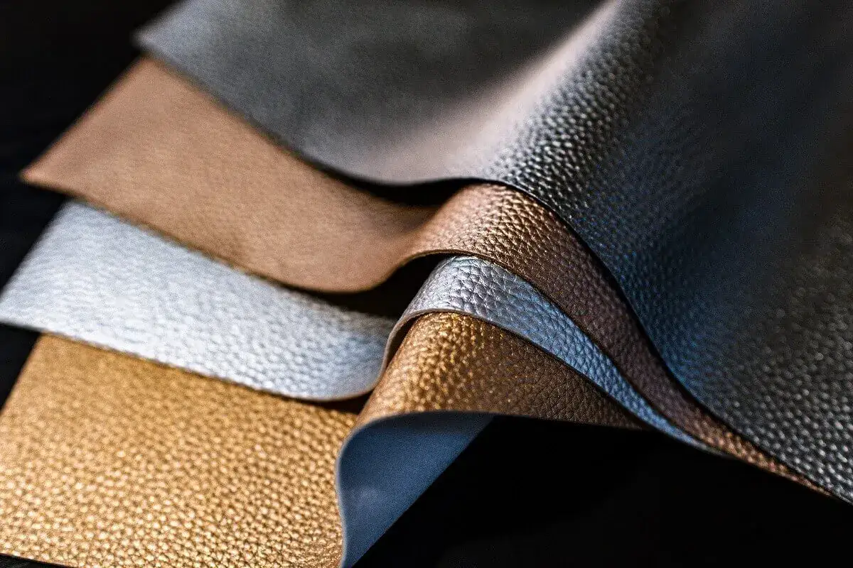 Variedad de tipos de cuero en tonos metálicos: dorado, plateado, bronce y gris oscuro, con texturas granuladas y suaves.