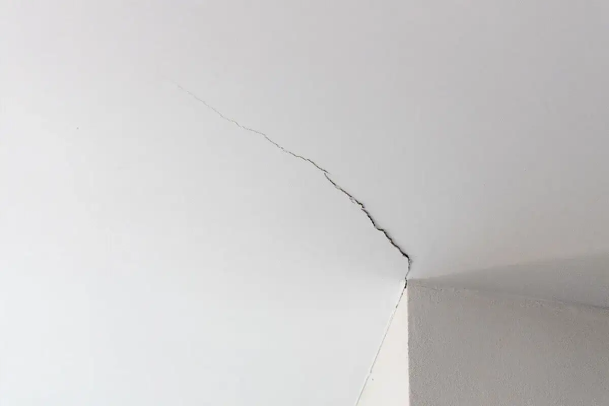 Fissure sur un plafond blanc, signe d'une trame de rénovation nécessaire.
