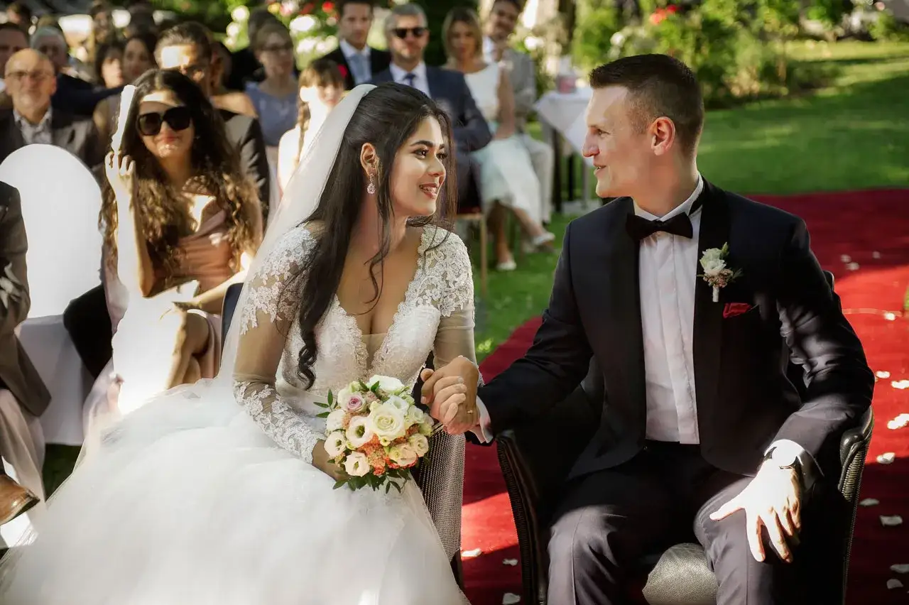 Brautpaar hält Händchen bei einer wunderschönen Zeremonie. Welche Hochzeiten gibt es? Diese hier ist voller Liebe und Freude.