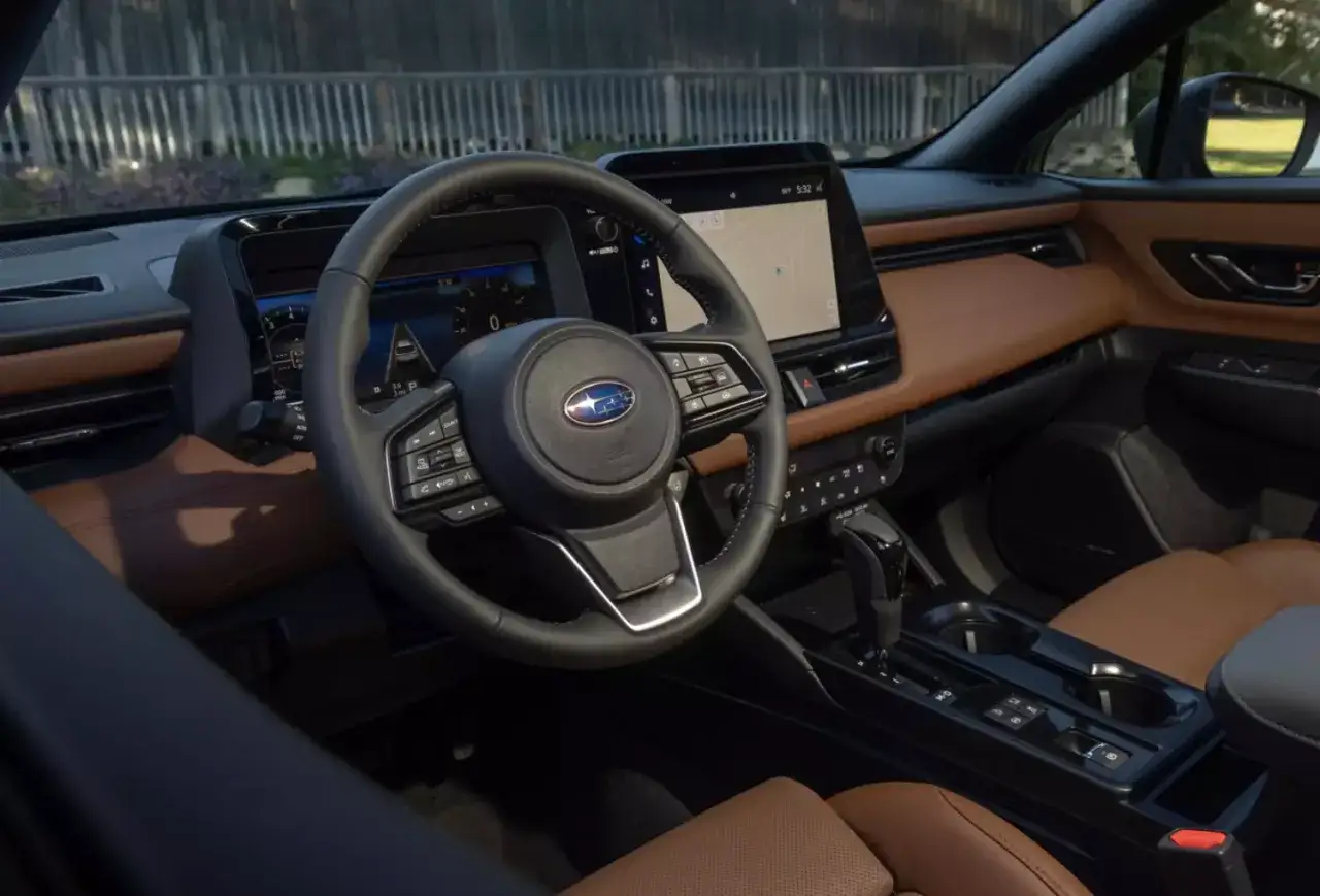 Wnętrze Subaru Outback 2026 z brązową tapicerką, dużym ekranem multimedialnym i cyfrowymi zegarami.