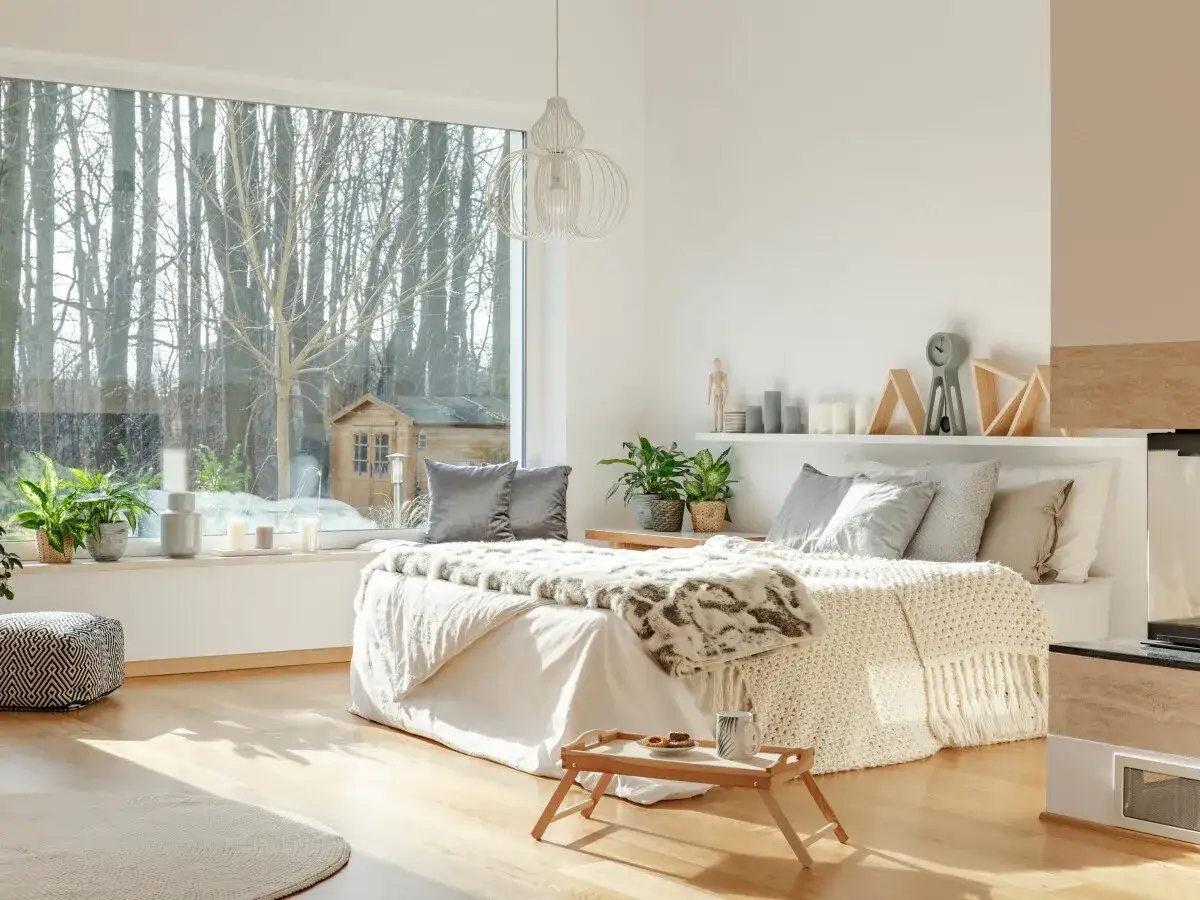 Habitación luminosa con cama acogedora, plantas y gran ventanal que invita a la calma, ideal para el feng shui.
