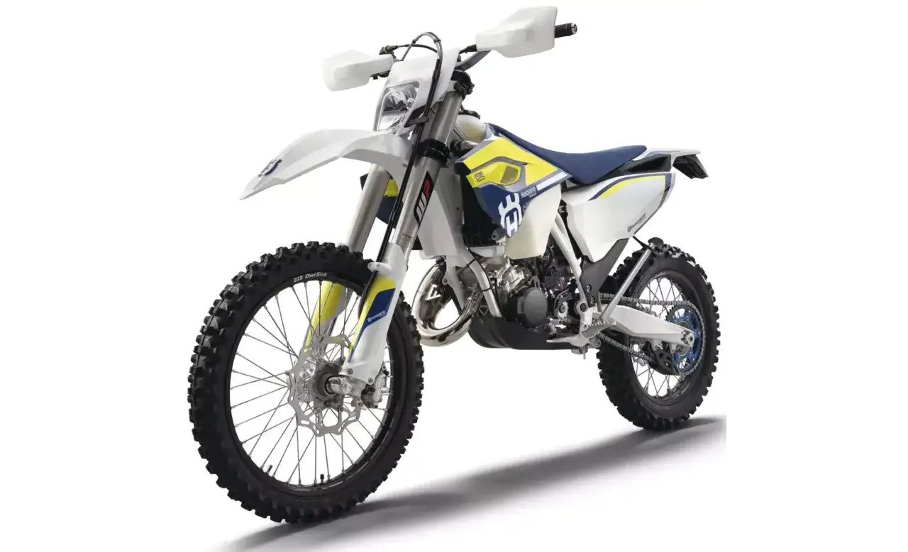 Biały motocykl Husqvarna TE 125 z niebieskimi i ż&oacute;łtymi akcentami, gotowy na terenowe wyzwania.