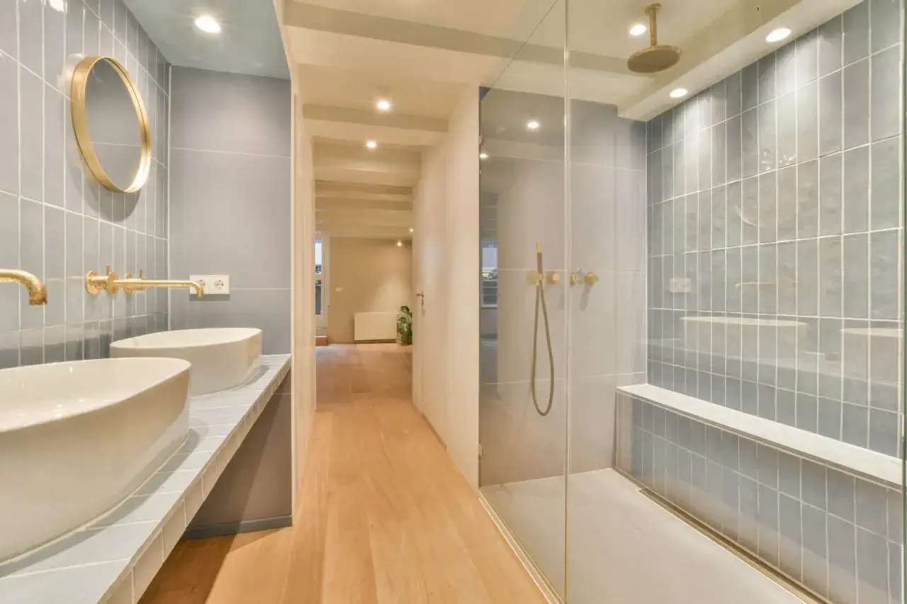 Moderna doccia in muratura con pareti piastrellate grigio chiaro, panca integrata e soffione a pioggia. Ideale per chi cerca idee bagno eleganti.