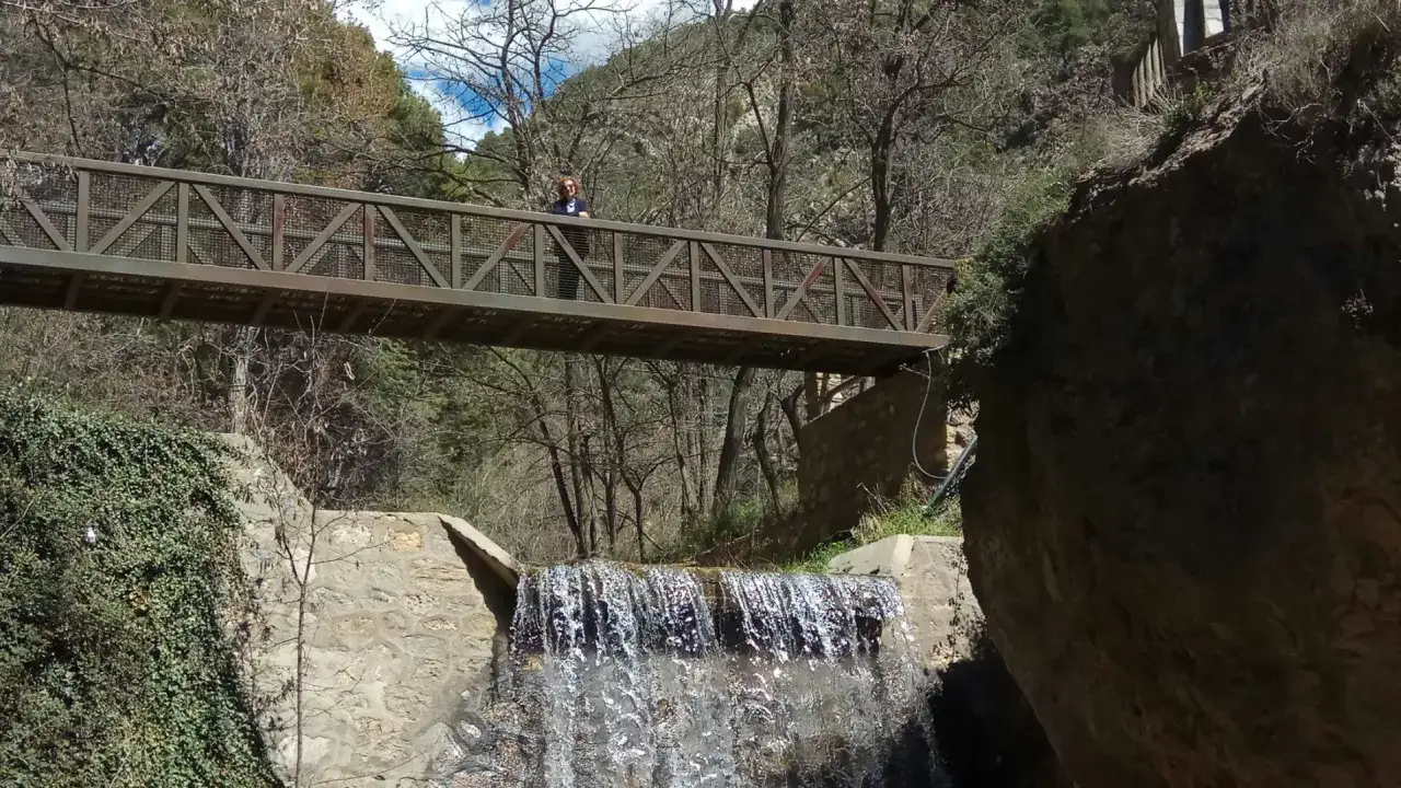 Puente metálico sobre cascada en la fabriquilla laujar. Una persona sonríe en el puente.