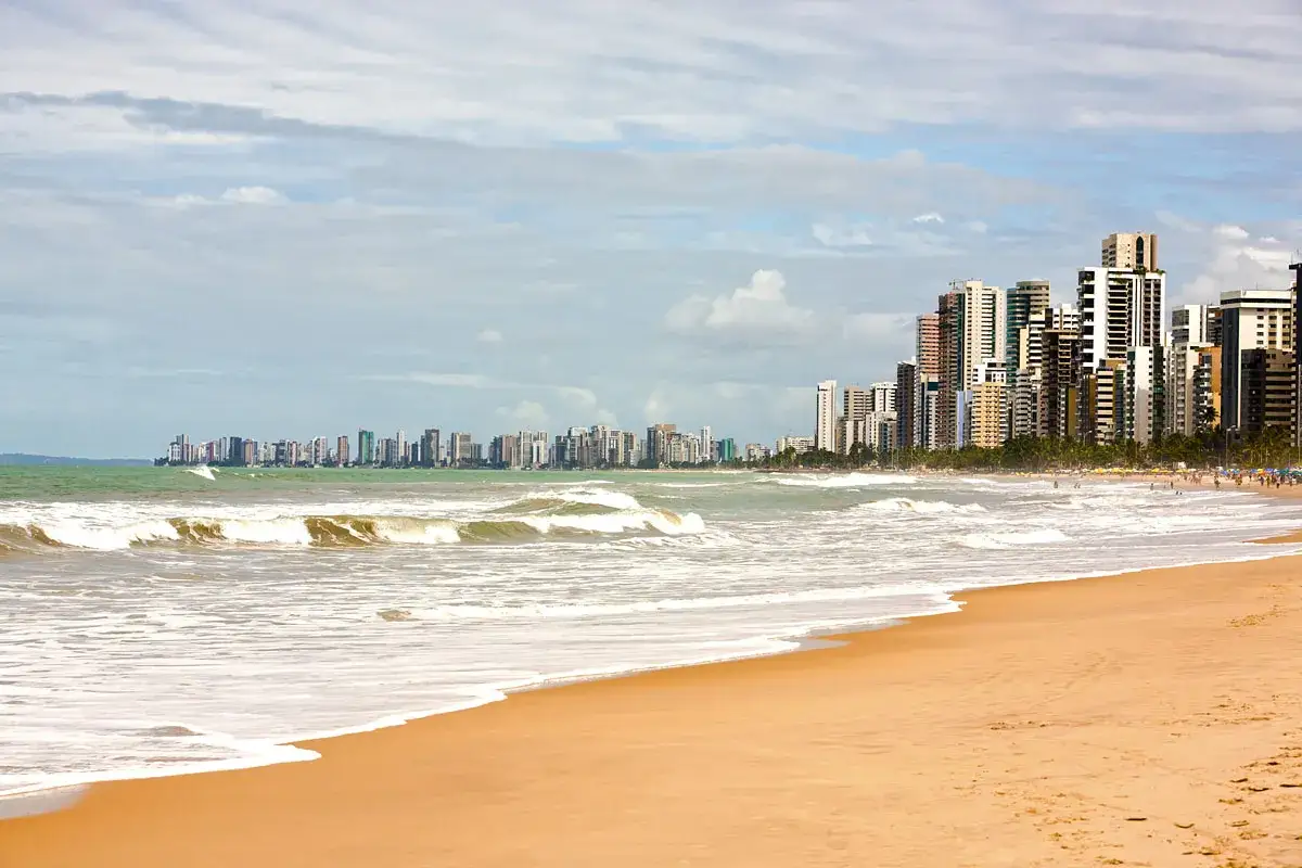 Strand mit Wellen und einer Skyline von Hochh&auml;usern in Recife, Brasilien.