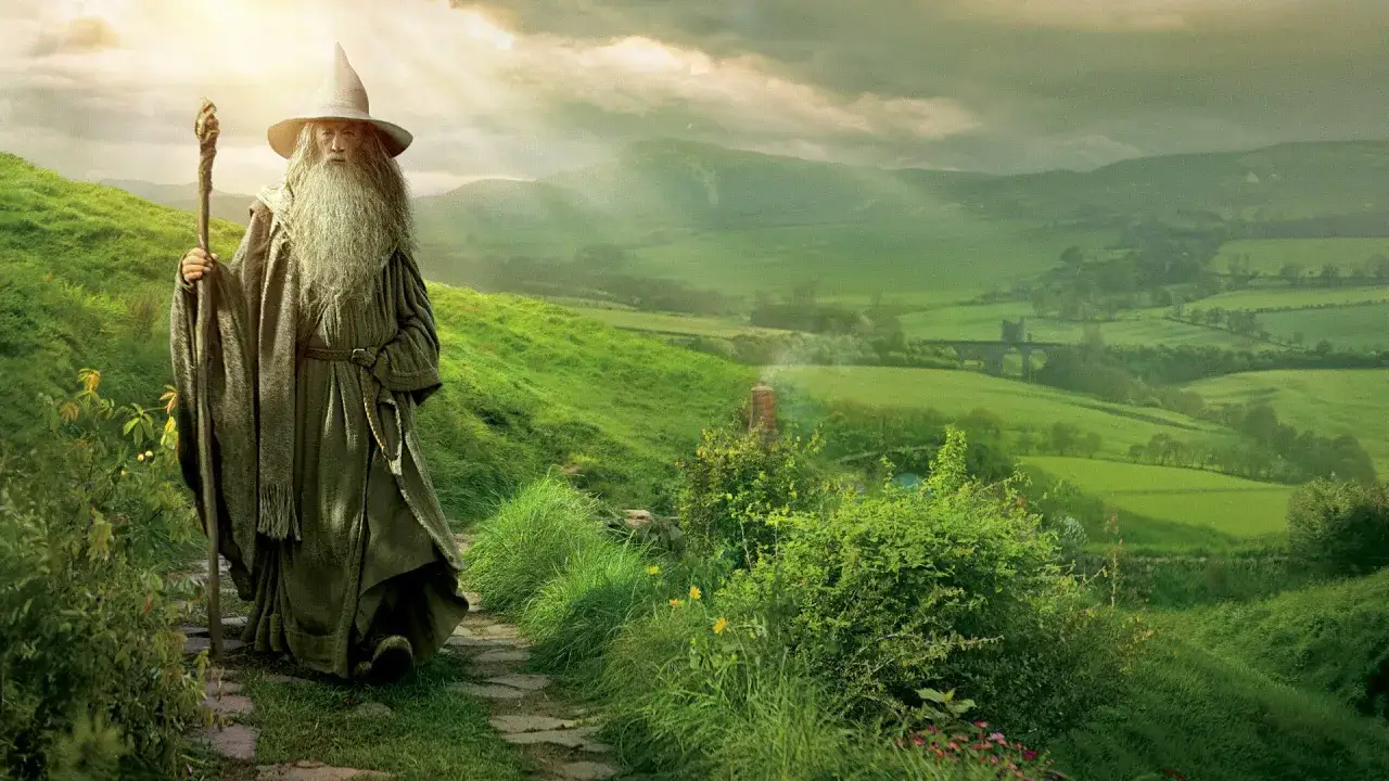 Gandalf, autor Władcy Pierścieni, stoi na ścieżce wśr&oacute;d zielonych wzg&oacute;rz.