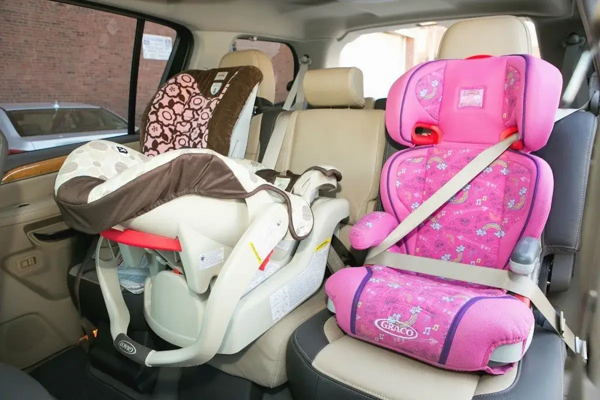 Asiento de coche rosa y marrón en un coche. Aprende como colocar silla grupo 2 3 sin isofix.