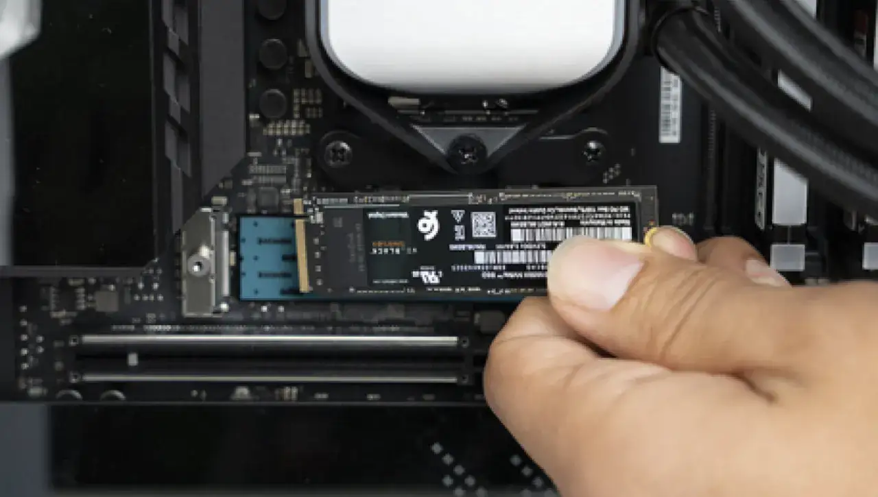 Eine Hand schiebt eine M.2 SSD in den Steckplatz auf einem Computer-Motherboard.