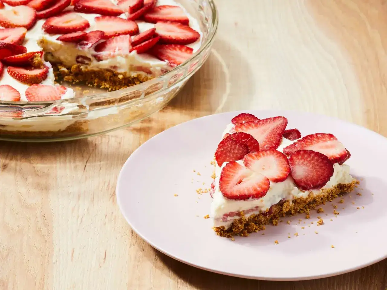 Ein St&uuml;ck zuckerfreien Kuchen mit Erdbeeren auf einem Teller, daneben der ganze Kuchen in einer Glasform.