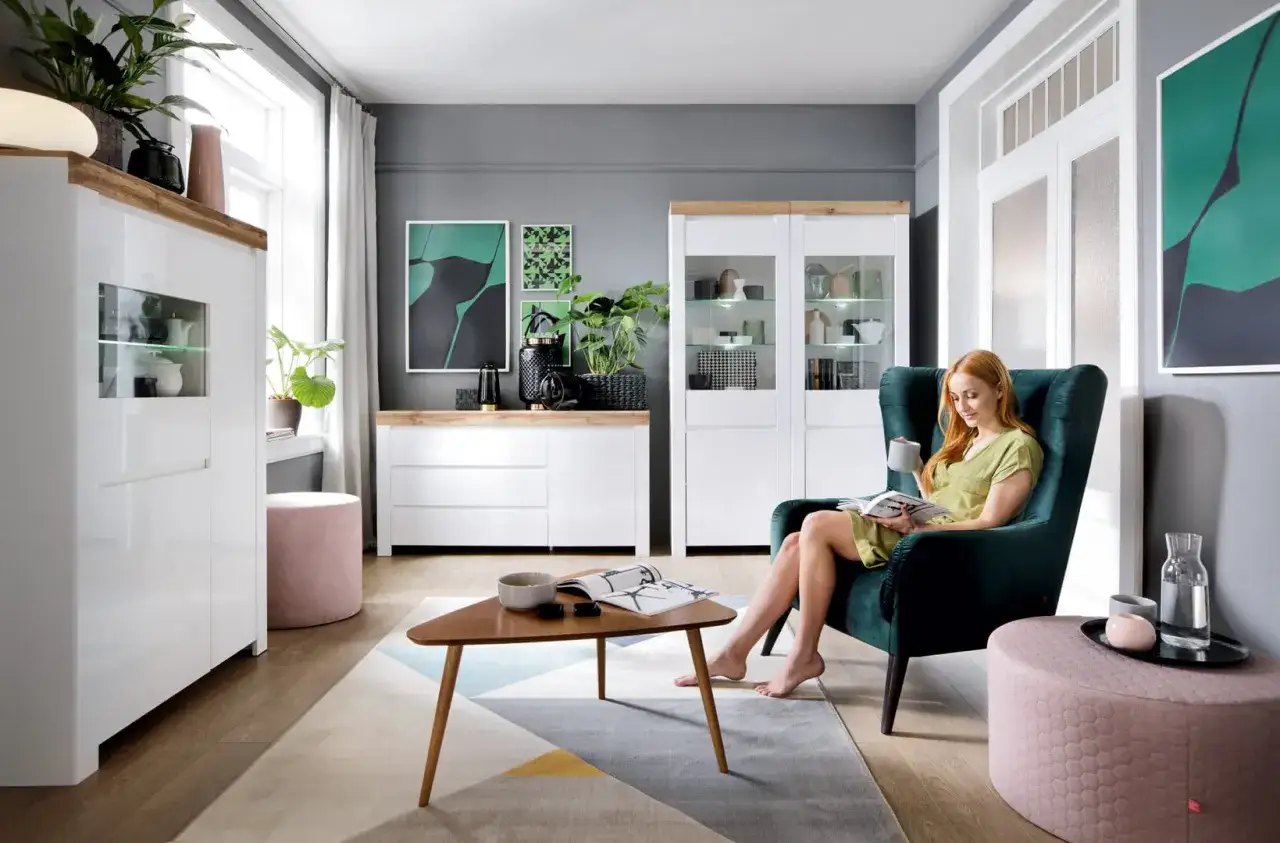 Zielony salon inspiracje: kobieta czyta książkę w fotelu, nowoczesne meble, jasne kolory, rośliny.
