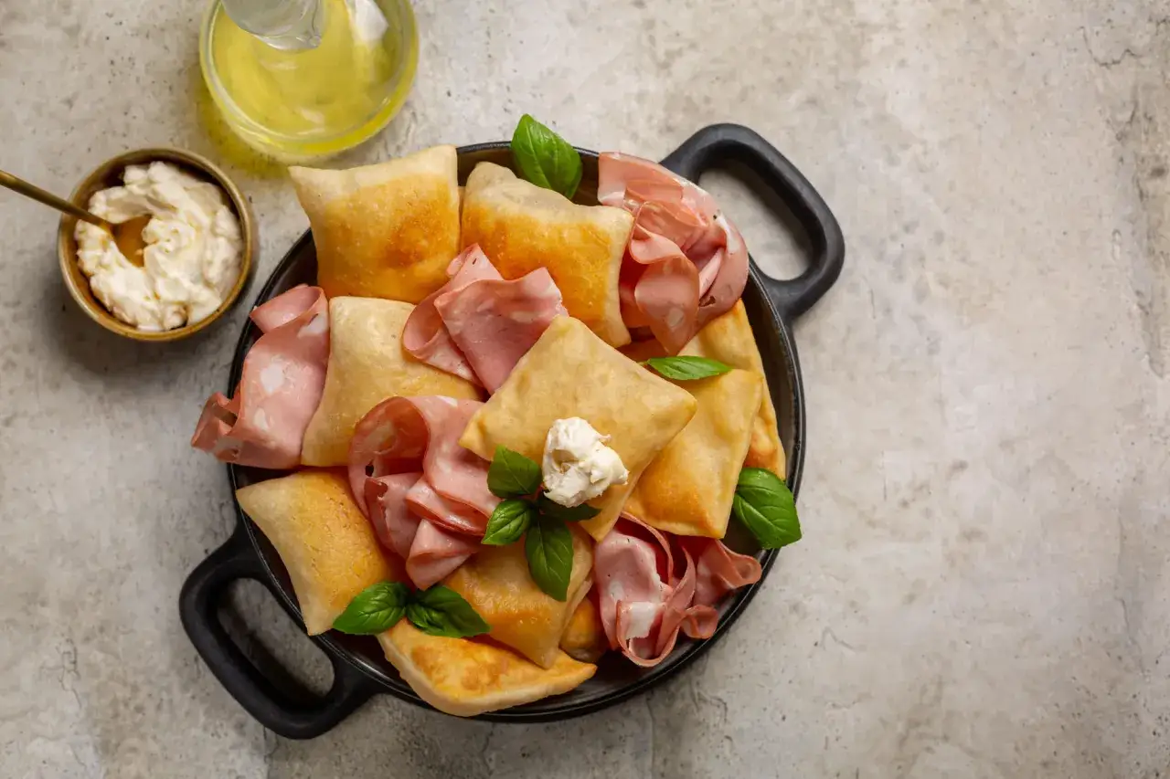 Piatto con crescentine fritte, mortadella e formaggio cremoso, un classico dei piatti tipici bolognesi.