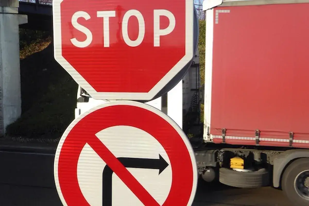 Znak STOP i zakaz skrętu w prawo. Ciężarówka czeka na decyzję, czy może jechać.