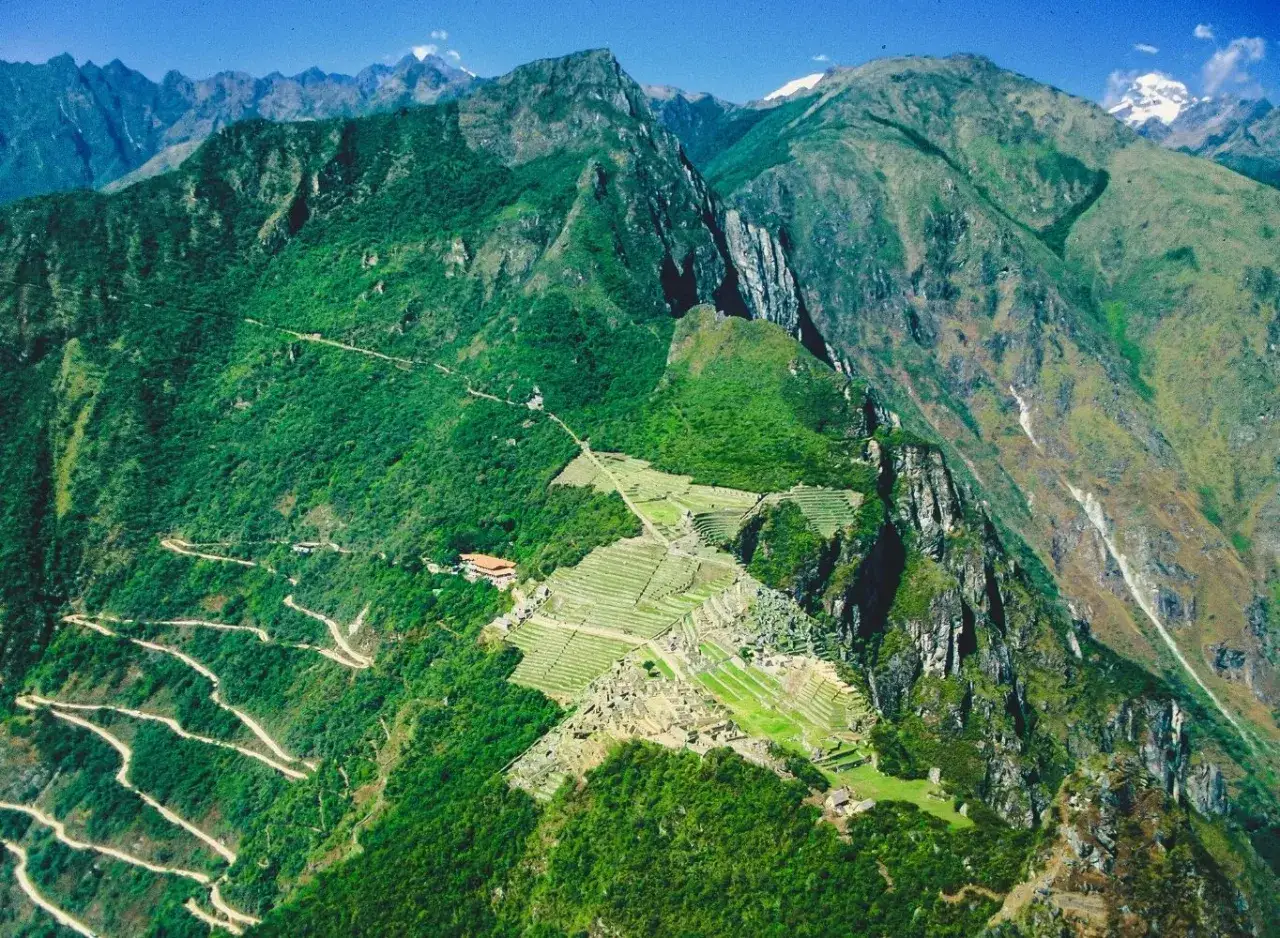 Widok na Machu Picchu z lotu ptaka. Kręta droga prowadzi do ruin, a tarasy uprawne schodzą po zboczu. Niezapomniana machu picchu wycieczka.