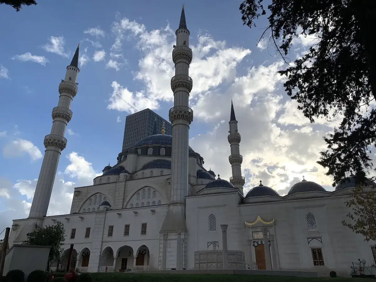 Imponująca budowla meczetu z minaretami, symbol albańskiej religii, na tle błękitnego nieba z chmurami.