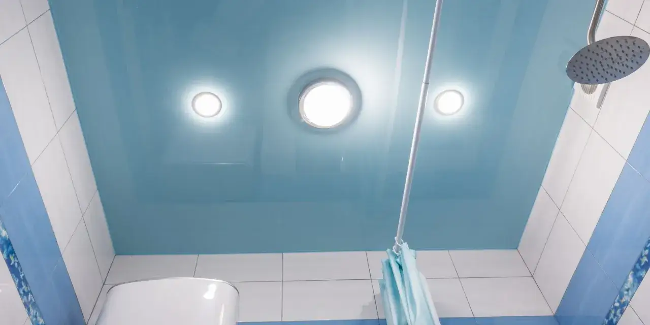 Un plafond bleu brillant pour la salle de bain, avec des spots lumineux et une douche.