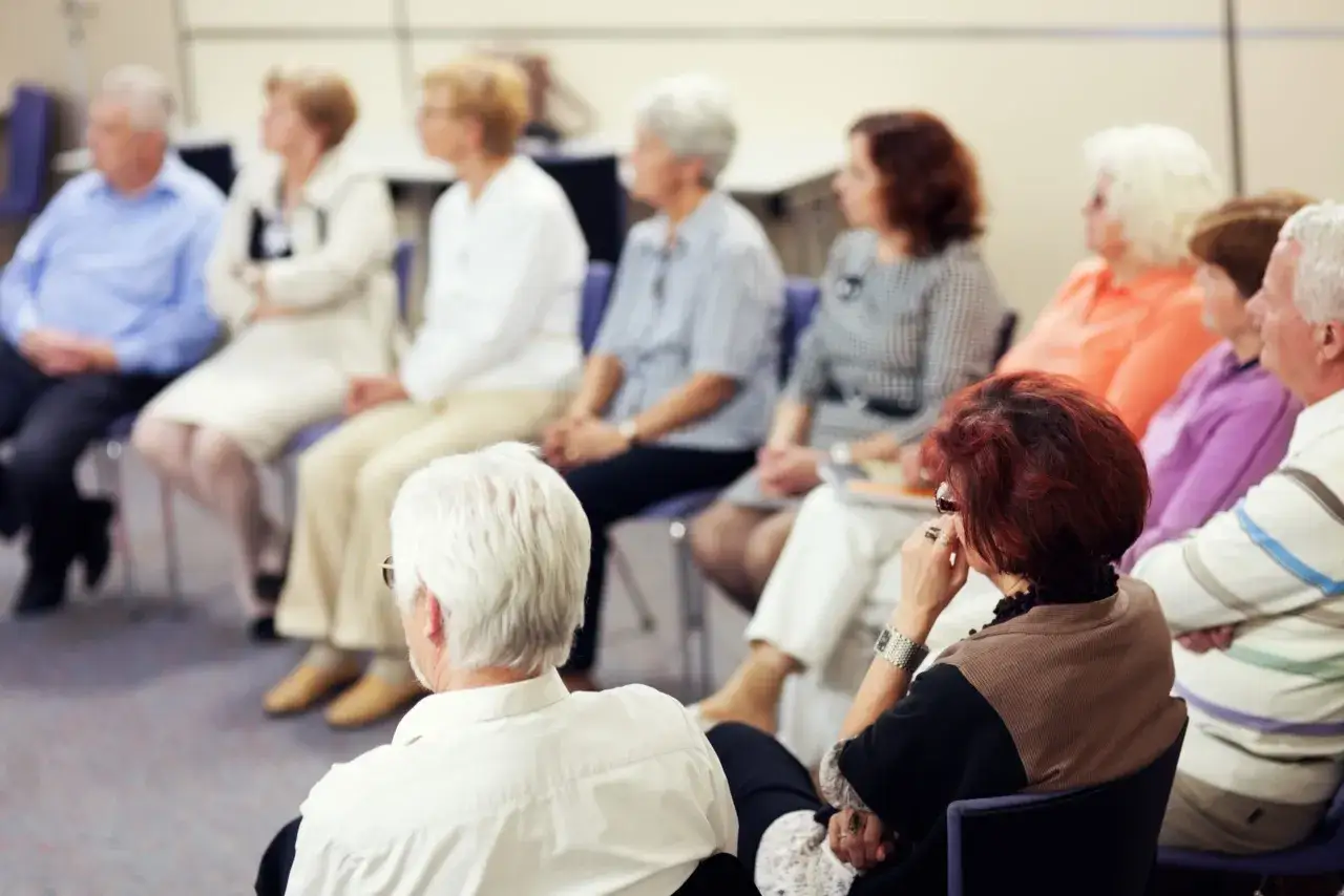 Senioren in einer Gruppe, die über **Depressionen im Alter** sprechen. Sie sitzen auf Stühlen und hören aufmerksam zu.