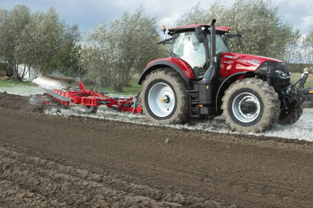 Czerwony traktor Case IH z pługiem orze pole. To idealny czas orki 1 ha, przygotowuje ziemię pod zasiewy.