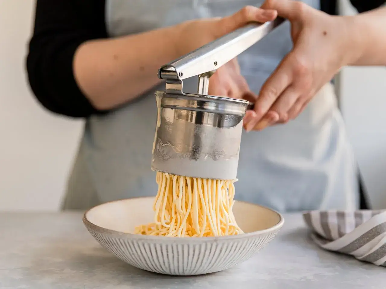 Ein Spaghettieis-Dessert wird mit einer Presse in eine Schüssel geformt.