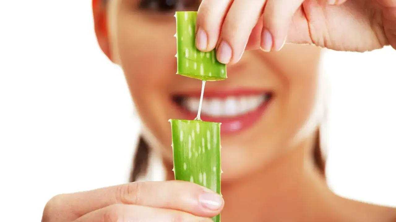 Frau h&auml;lt Aloe Vera St&uuml;cke, aus denen ein Tropfen Gel f&uuml;r die Hautpflege flie&szlig;t.