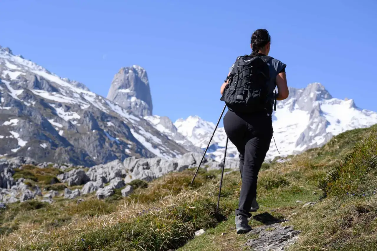 Senderista camina por las **rutas de Sotres**, con el Naranjo de Bulnes al fondo.