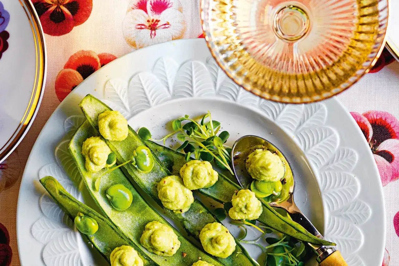 Fagiolini verdi con spuma di pecorino e fave fresche, guarniti con germogli e serviti su un piatto bianco decorato.