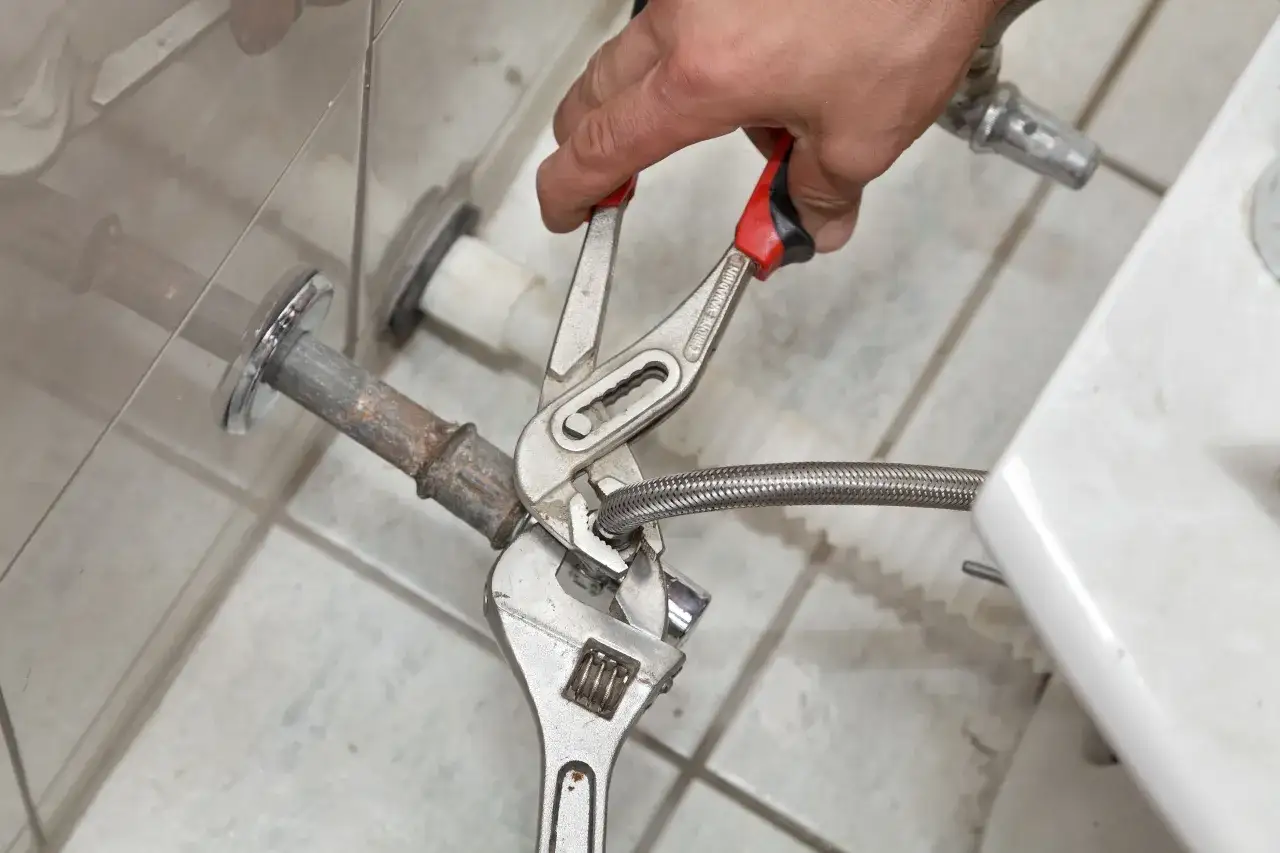 Manos con herramientas desconectan tuber&iacute;a flexible para quitar bidet.