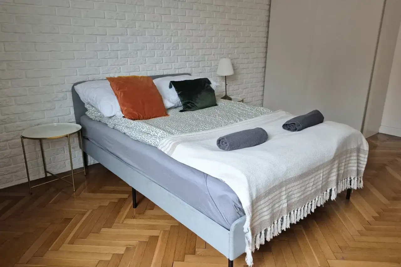 Łóżko z narzutą i poduszkami. Czy to powód, dlaczego rząd chce karać grzywną 50 tysięcy złotych za brak wpisu do rejestru najmu?