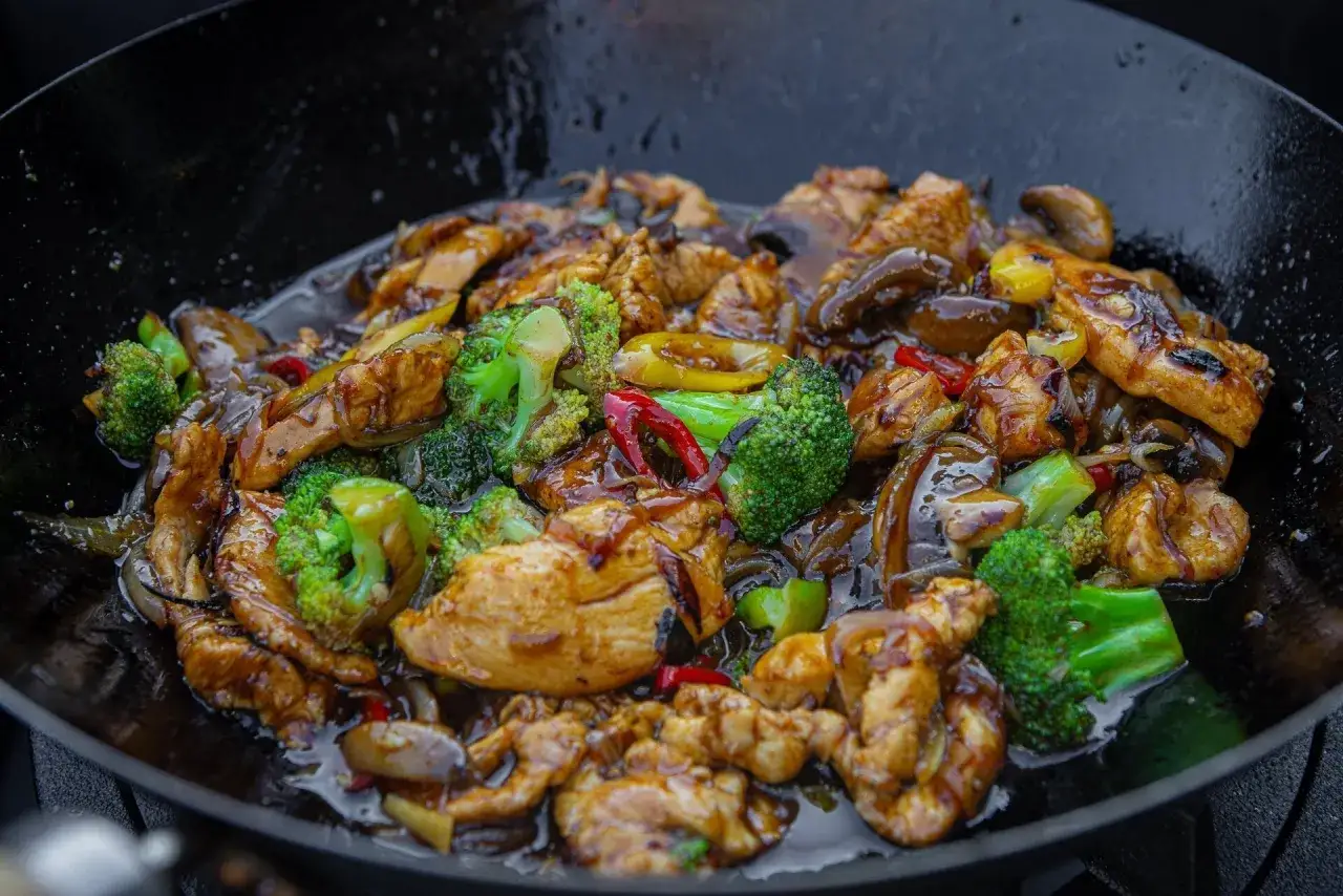En wok med saftig kinesisk kyckling, broccoli, champinjoner och chili i en glansig sås.