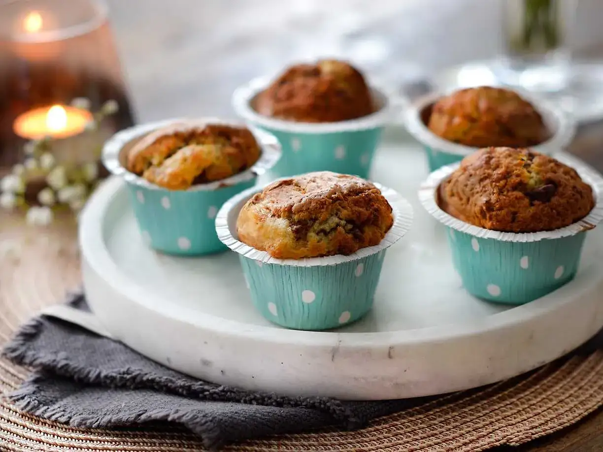 Nybakade muffins i ljusbl&aring;a pappersformar med prickar, perfekta att baka i airfryer f&ouml;r en snabb fika.