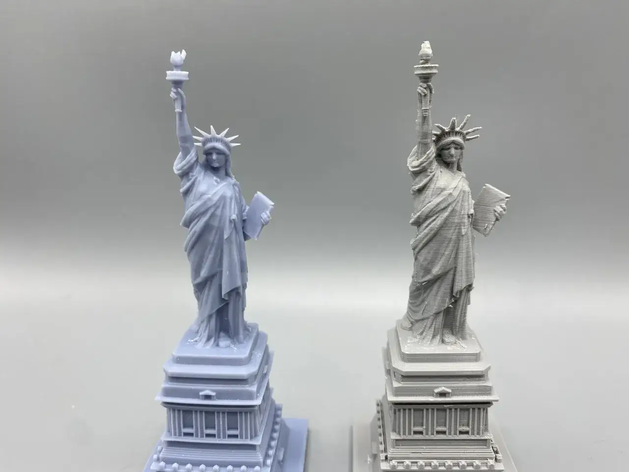 Two Statue of Liberty models: one smooth, likely resin vs. filament 3d printer with visible layer lines.