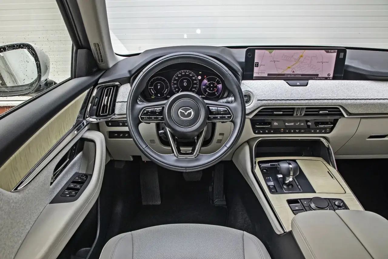 Wnętrze Mazdy CX-60 z ekranem nawigacji i cyfrowymi zegarami. Zastanawiasz się nad mazda cx 60 cena? Ten luksusowy SUV oferuje komfort i nowoczesne technologie.