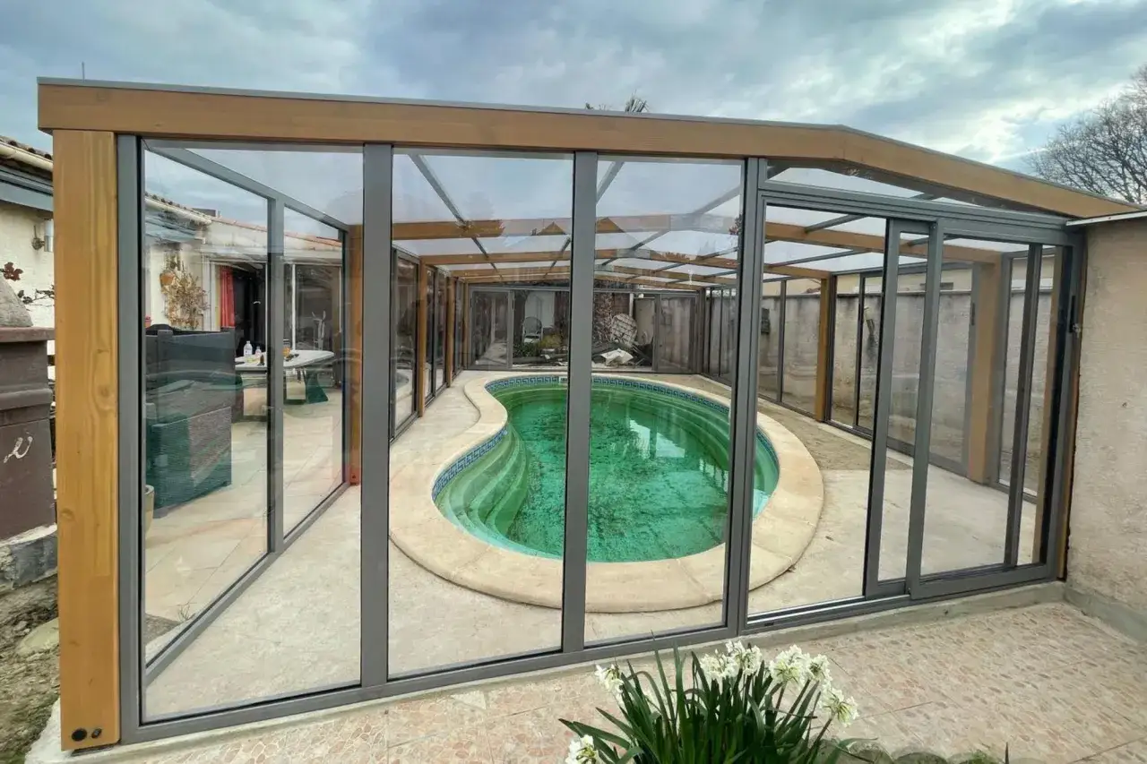 Abri de piscine hors sol moderne en verre et bois, offrant une vue sur la piscine. Id&eacute;al pour apprendre comment fabriquer un abri piscine hors sol.