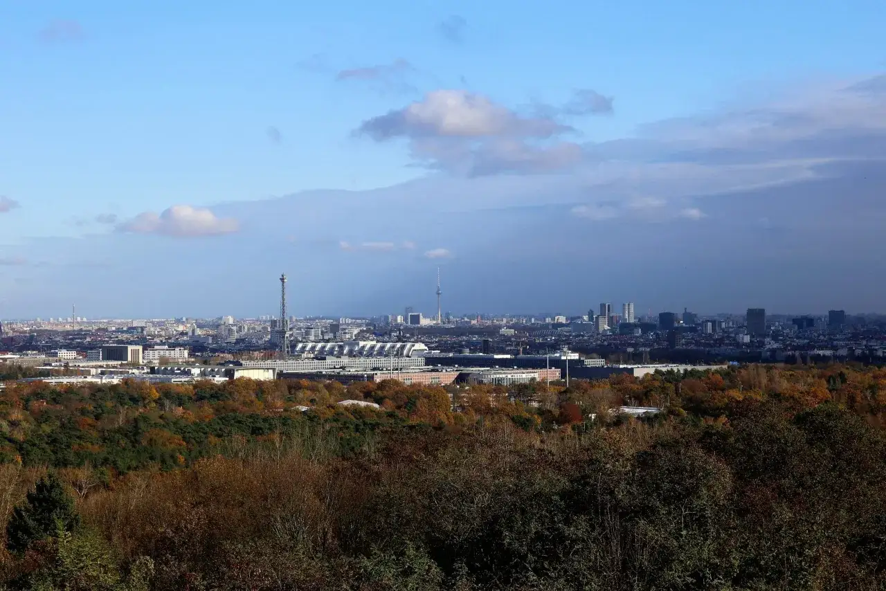 Blick vom Teufelsberg auf Berlin im Herbst. Die Stadt erstreckt sich unter einem blauen Himmel mit Wolken.