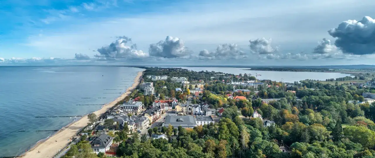 Widok na Mielno: plaża, morze, jezioro i zabudowania. Idealne miejsce, by sprawdzić, co warto zobaczyć w Mielnie.
