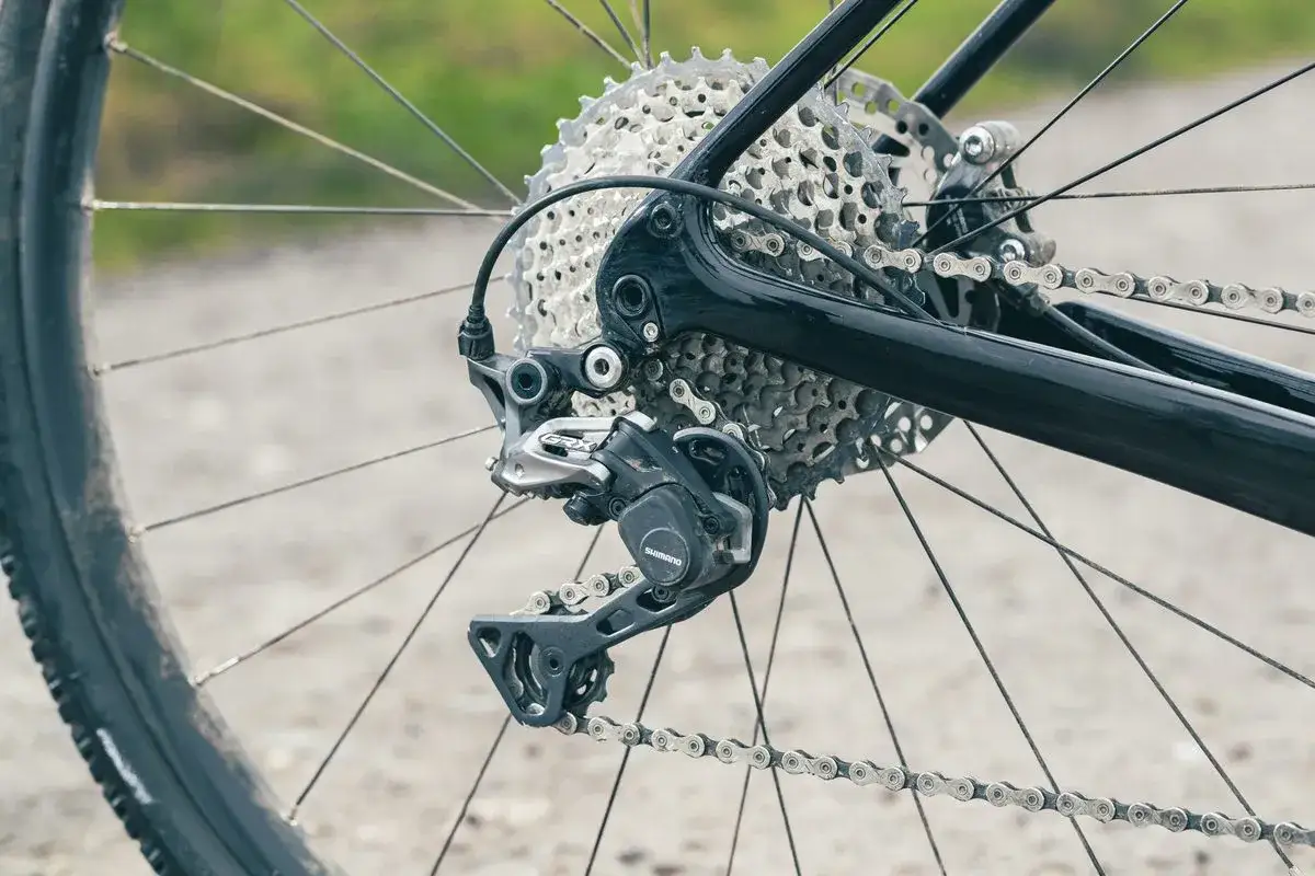 Zbliżenie na tylną przerzutkę rowerową Shimano GRX, pokazującą jeden z rodzajów przerzutek rowerowych.