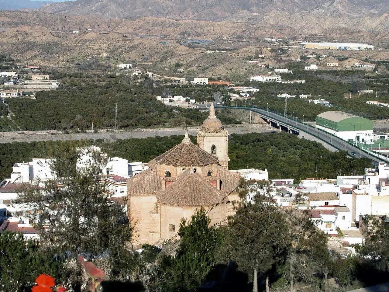 Iglesia de Gador, Almer&iacute;a, rodeada de vegetaci&oacute;n y casas blancas, con monta&ntilde;as al fondo.