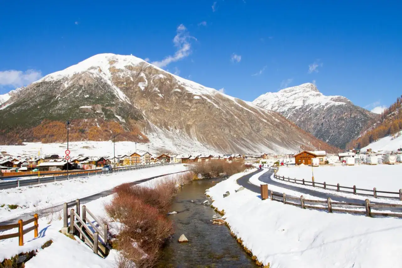 Livigno a novembre: un paesaggio innevato con montagne maestose, un fiume serpeggiante e un villaggio alpino. Ideale per scoprire cosa fare in questa perla delle Alpi.