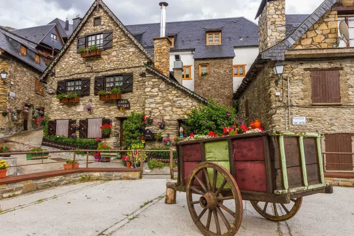 Carro decorado con flores frente a casas de piedra en pueblos del Valle de Ar&aacute;n.