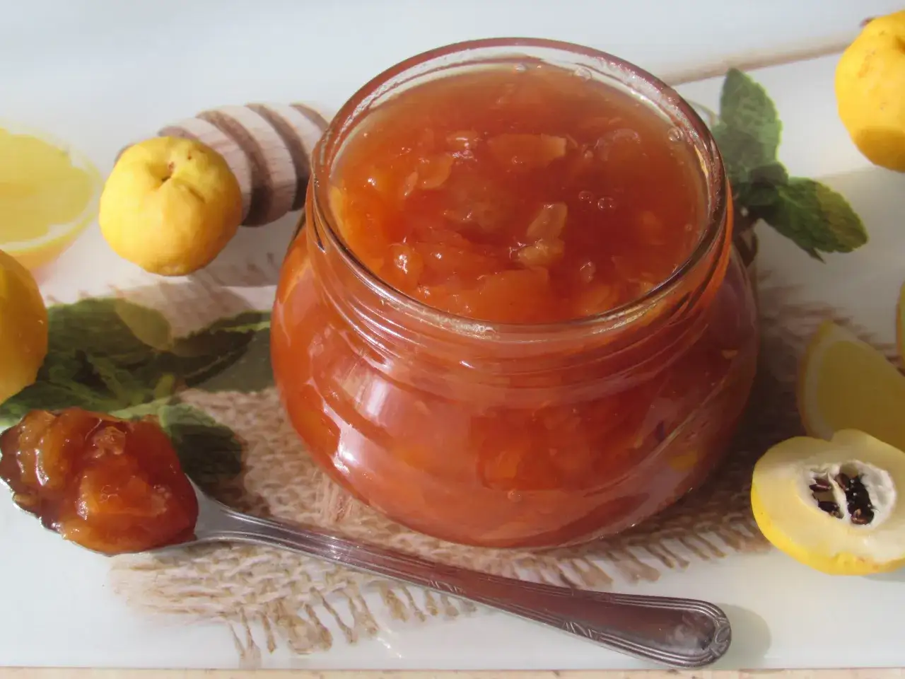 Słoik pełen aromatycznej konfitury z pigwy, idealnej do herbaty. Obok leżą świeże owoce i plasterki cytryny.