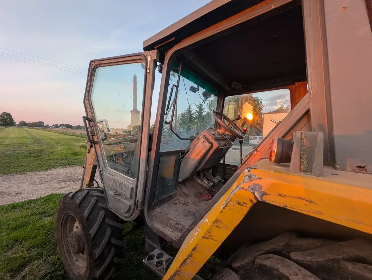 Montaż szyby w traktorze Renault. Zachodzące słońce oświetla kabinę i pole.
