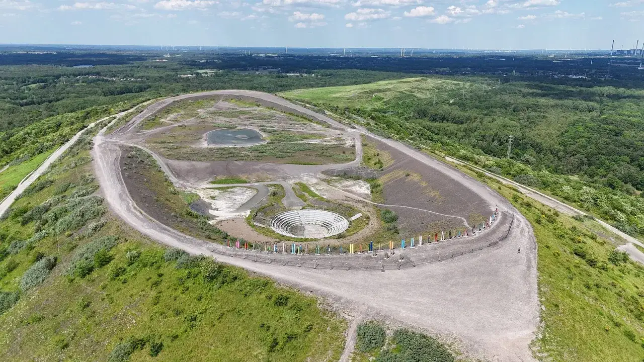 Gr&uuml;n bewachsene Halde mit Freilichtb&uuml;hne und bunten Stelen, Teil des Landschaftsparks **Prosper Haniel**.