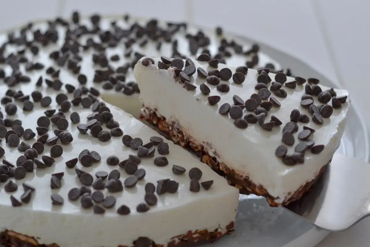 Deliziosa torta con yogurt greco 150 gr, ricoperta di gocce di cioccolato fondente. Una fetta è appena stata servita.
