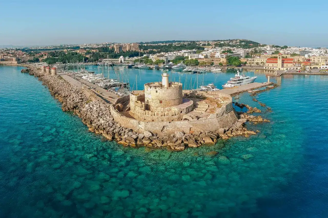 Festung am Eingang des Hafens von Rhodos Stadt, mit Yachten und der Stadt im Hintergrund.