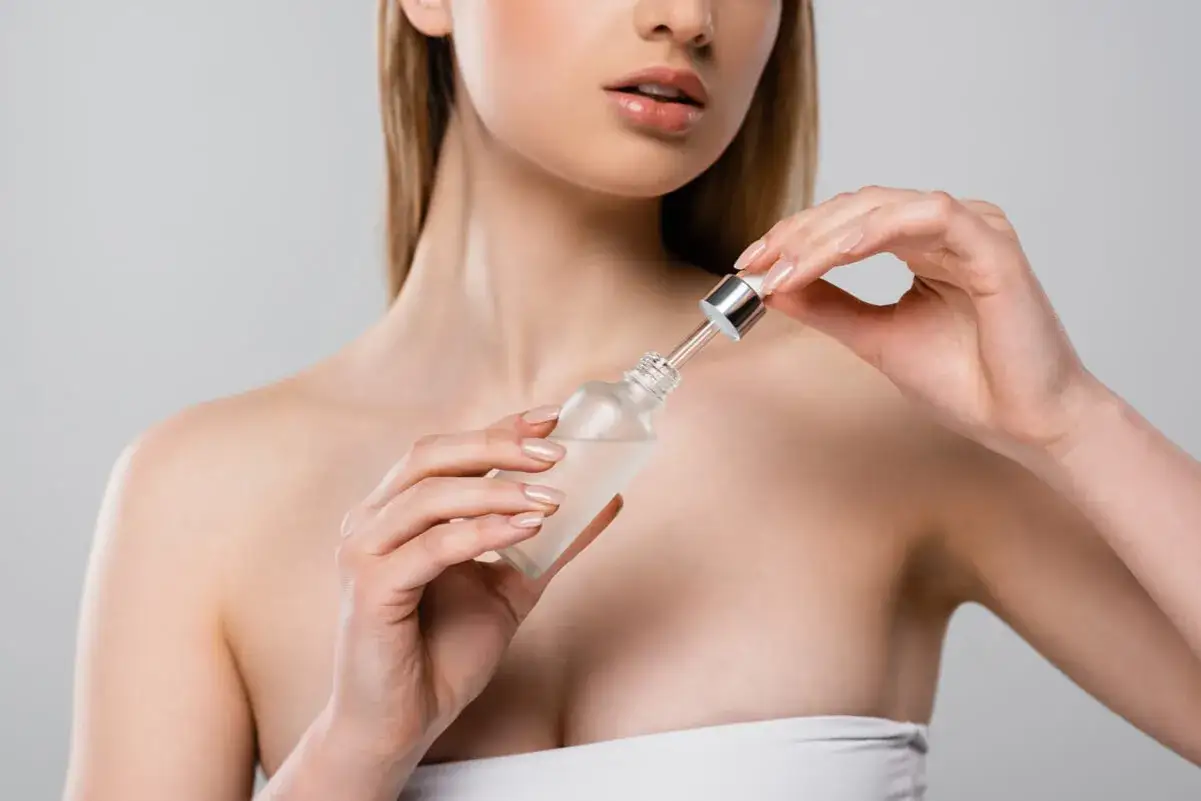 Kobieta nakładająca serum z witaminą C na twarz
