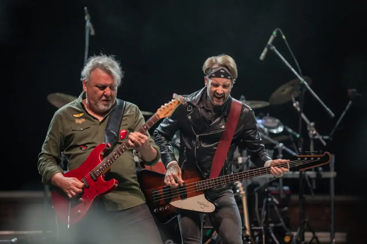 Dwóch muzyków na scenie, jeden gra na czerwonej gitarze, drugi na basie. To część składu Polish Metal Alliance.