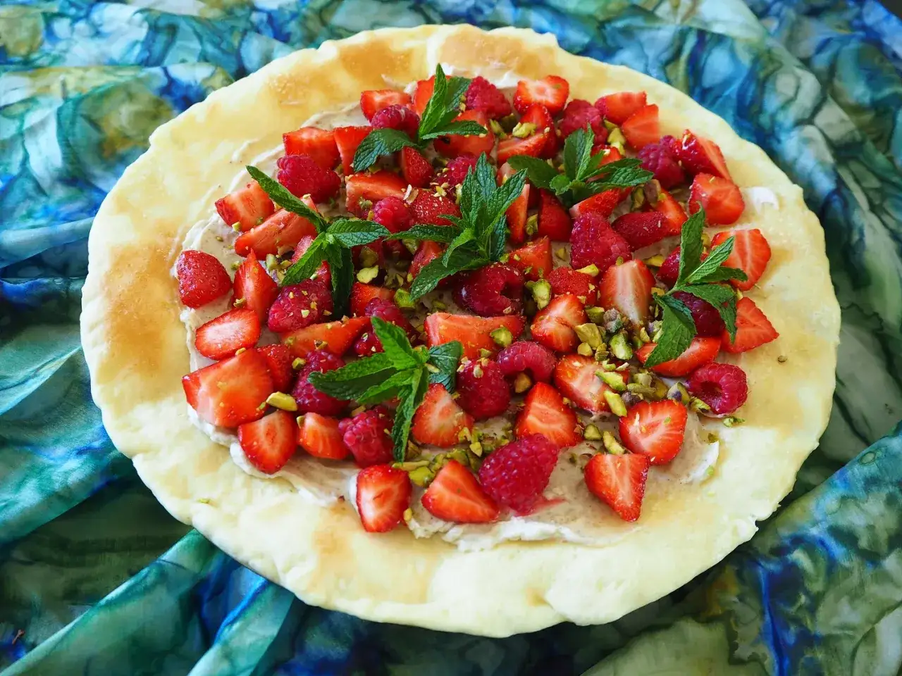 Letnia pizza z truskawkami, malinami, pistacjami i miętą na chrupiącym cieście.