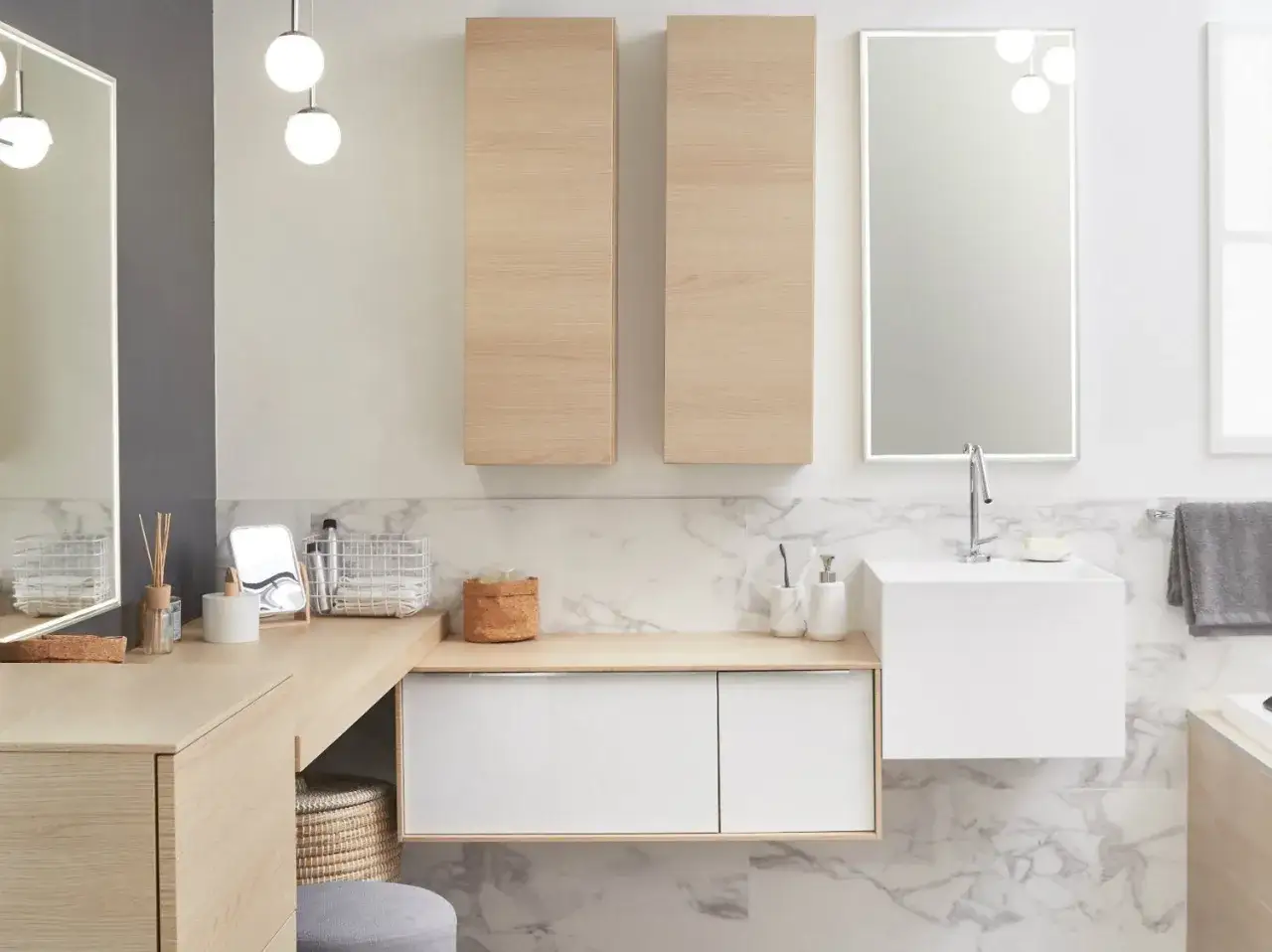 Salle de bain moderne avec un lavabo évier suspendu, des meubles en bois clair et un grand miroir lumineux.